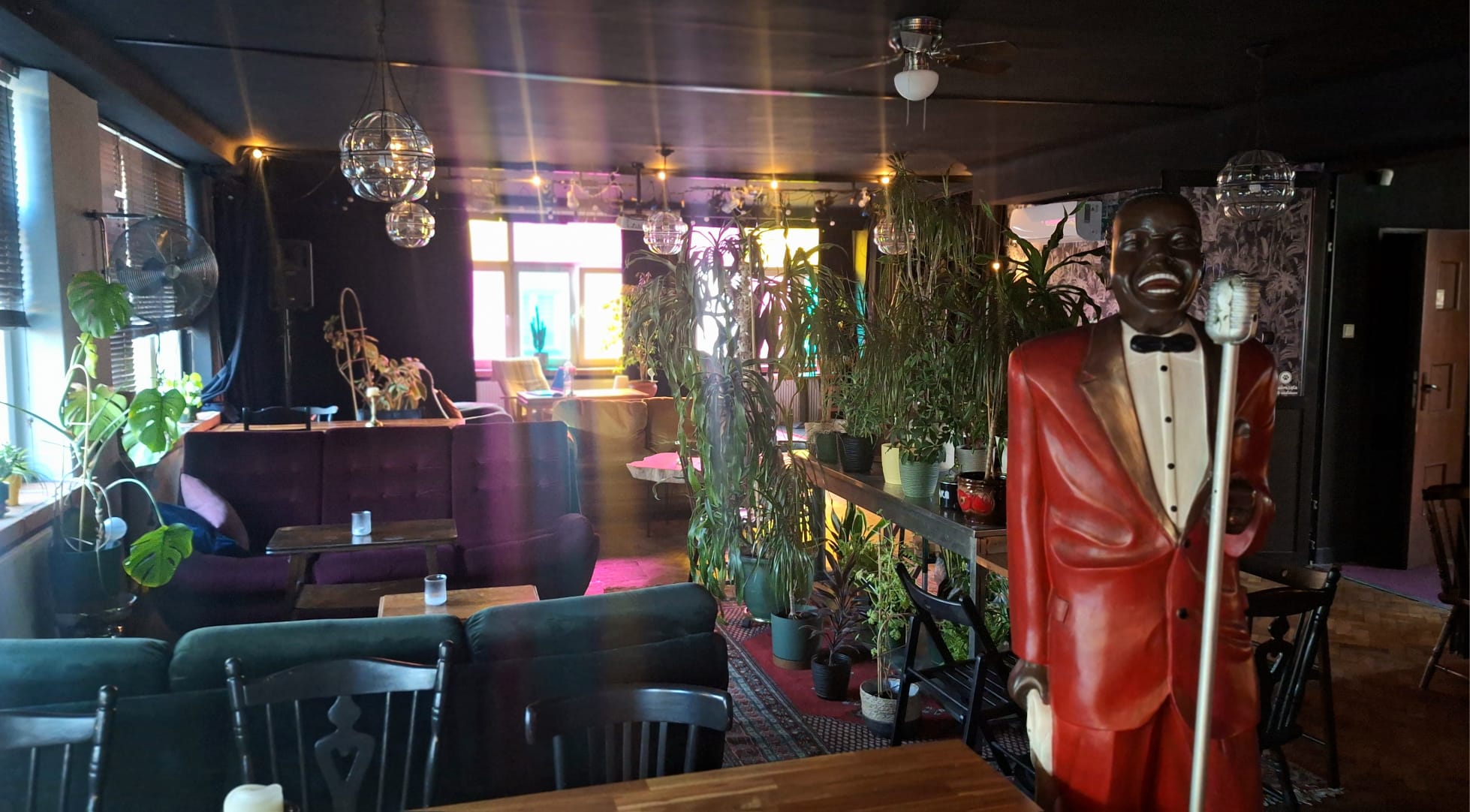 Sala klubokawiarni Poziom Wyżej — aksamitne kanapy, rośliny i figura wokalisty przy scenie